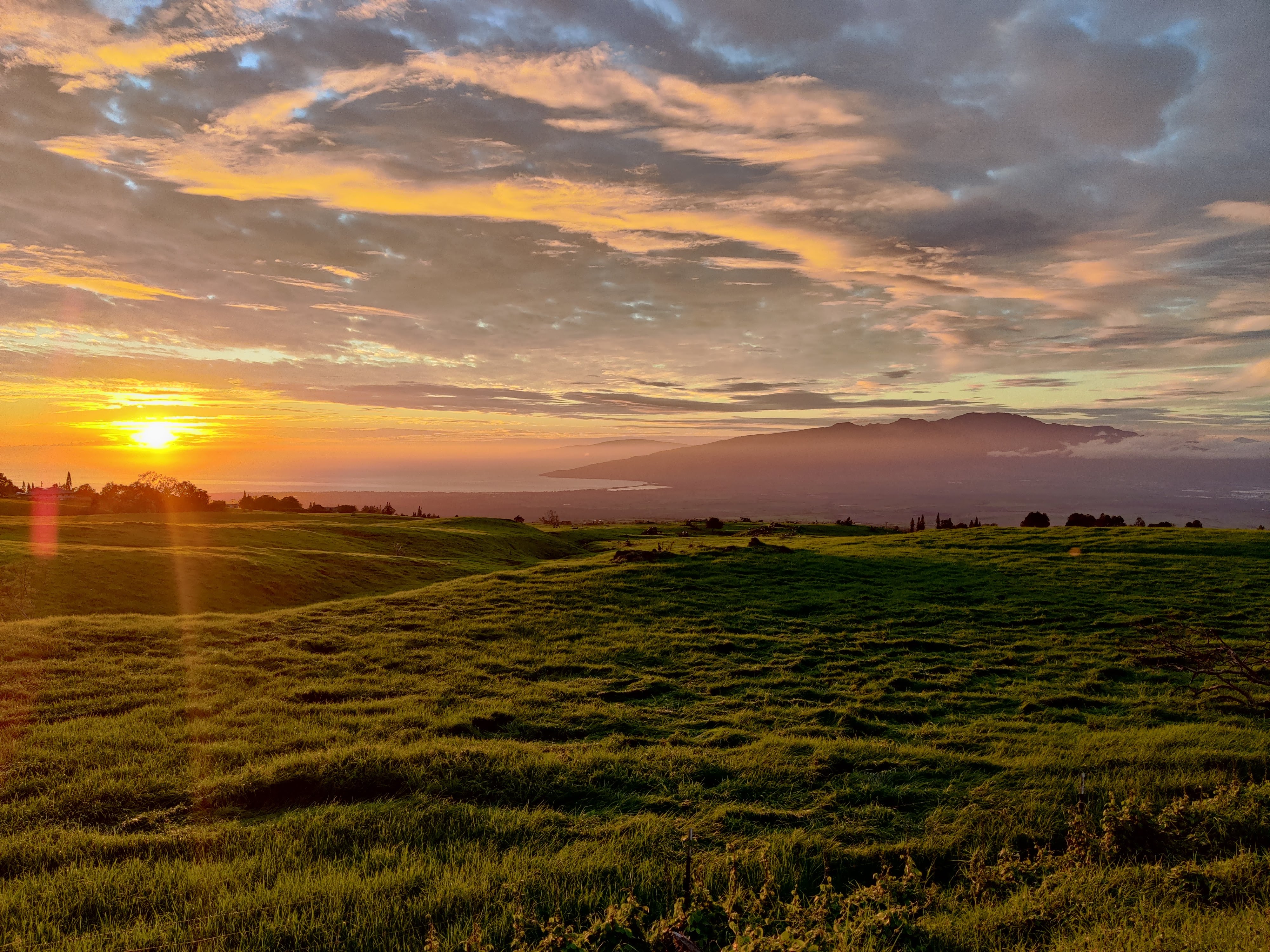 Sunset over rolling green hills and mountains on Maui